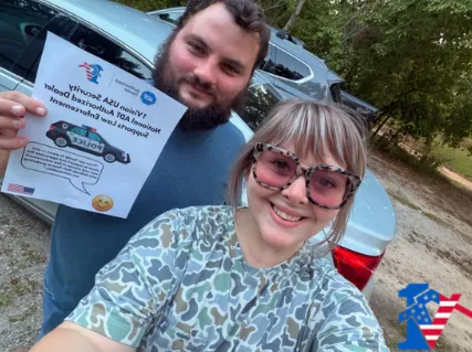 Alex and Adrianna smile in a selfie; he holds a 1 Vision USA flyer supporting law enforcement.