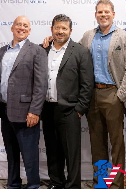 Byron, Frank and Luis in sport coats stand together in front of a 1 Vision Security backdrop.