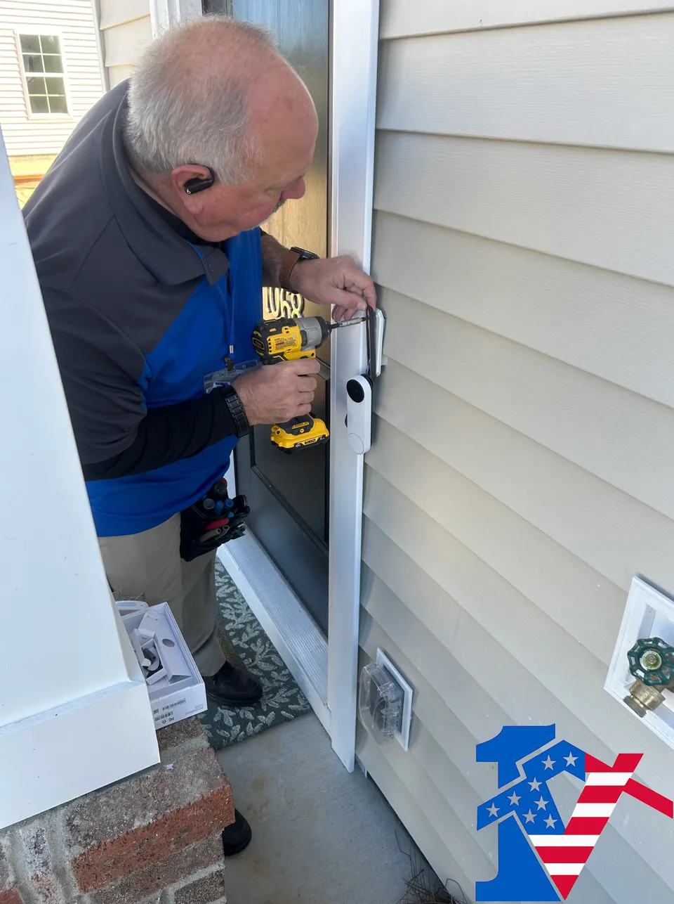 Mike uses a drill to mount a video doorbell beside a front door.