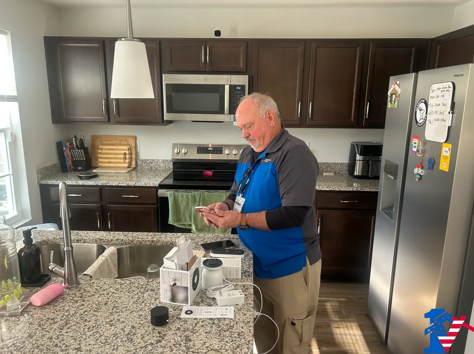 Mike sets up new cameras on his phone at a kitchen island with open camera boxes.